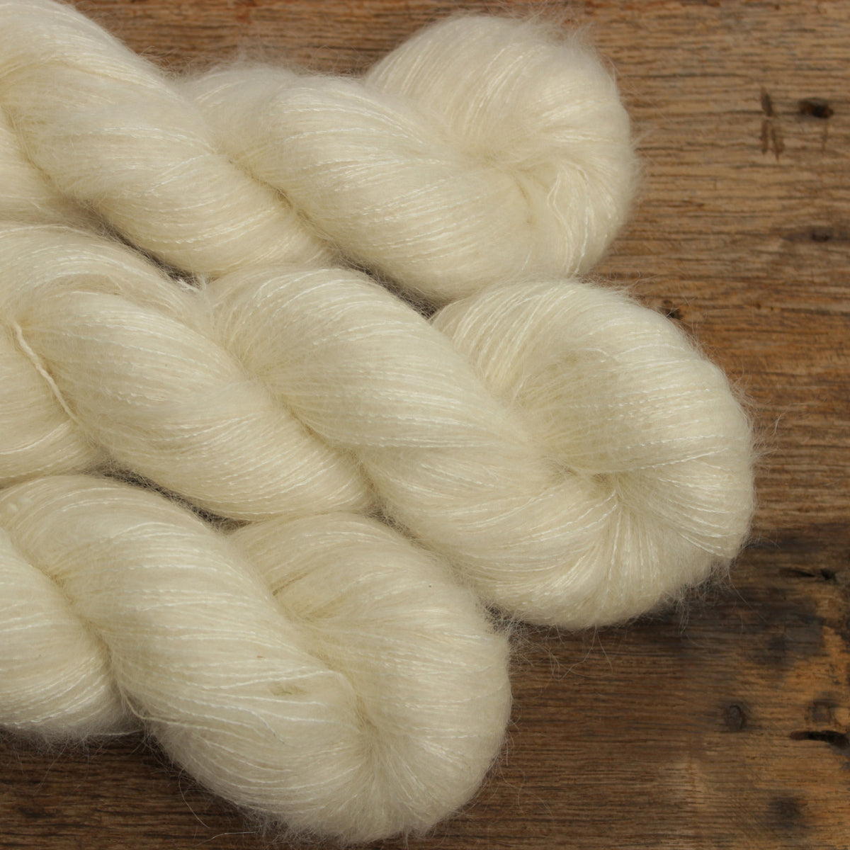 Kid Silk in der Farbe Ulla – cremefarbene Garnstränge mit feinem Mohairflausch auf Holzuntergrund