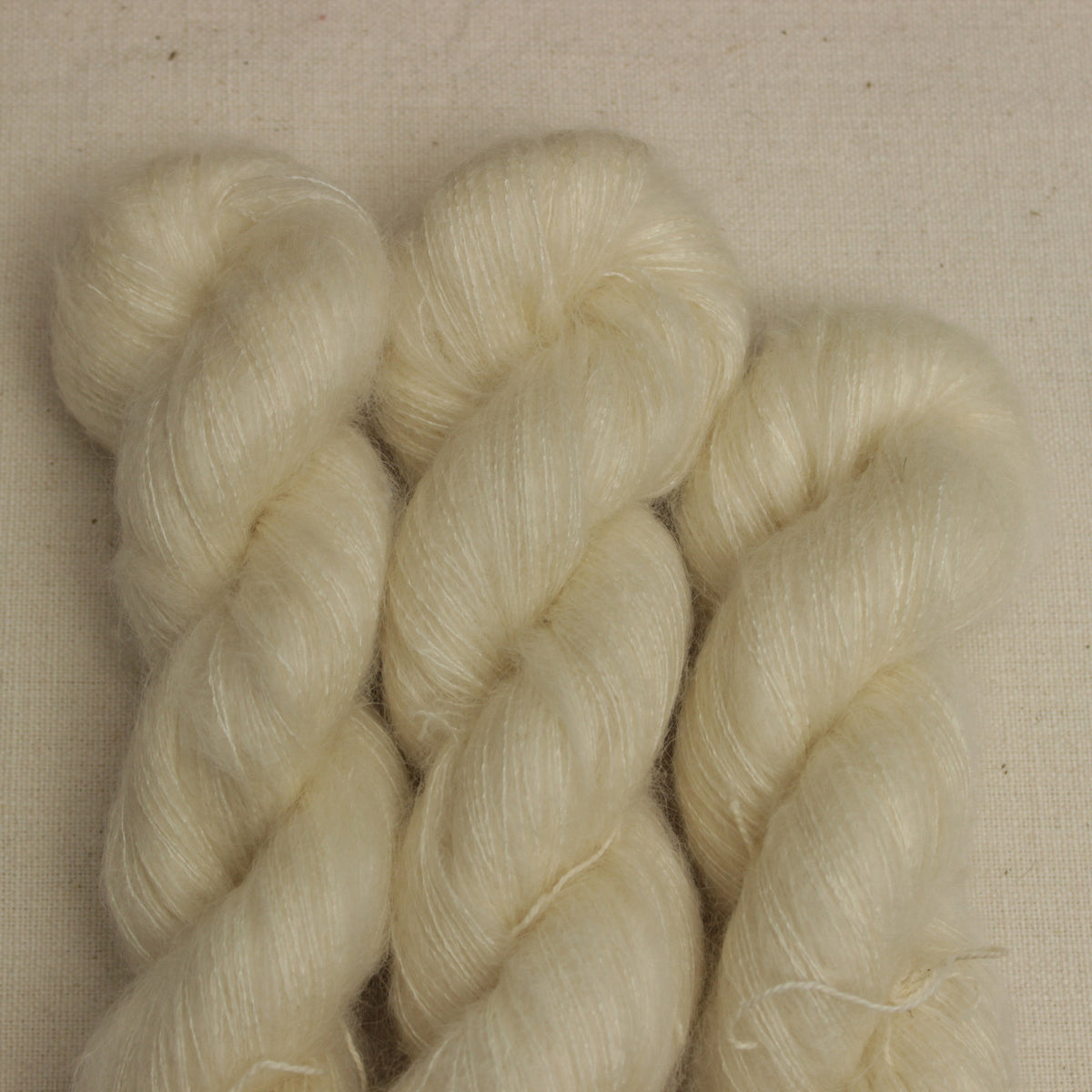 Kid Silk in der Farbe Ulla – cremefarbene Garnstränge mit feinem Mohairflausch auf Leinenuntergrund